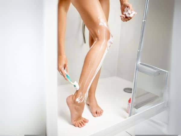 donna si depila le gambe con la lametta in doccia
