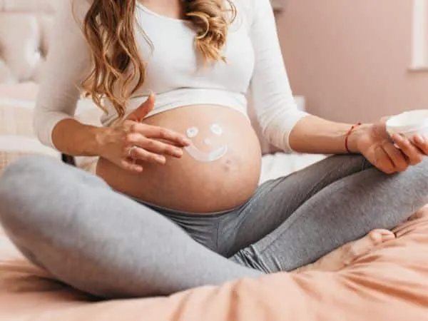 ragazza in gravidanza che mette una crema sulla pancia